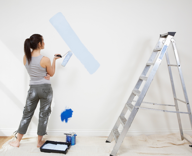 woman holding roller paint brush while painting the wall