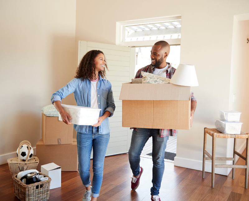 couple holding boxes while moving into new home