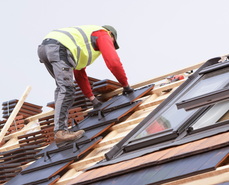 man placing a roof tile in the roof